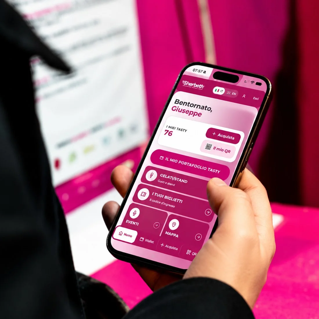 La WebApp Sherbeth aperta sul telefono, la sera, in piazza davanti al Teatro Massimo illuminato.